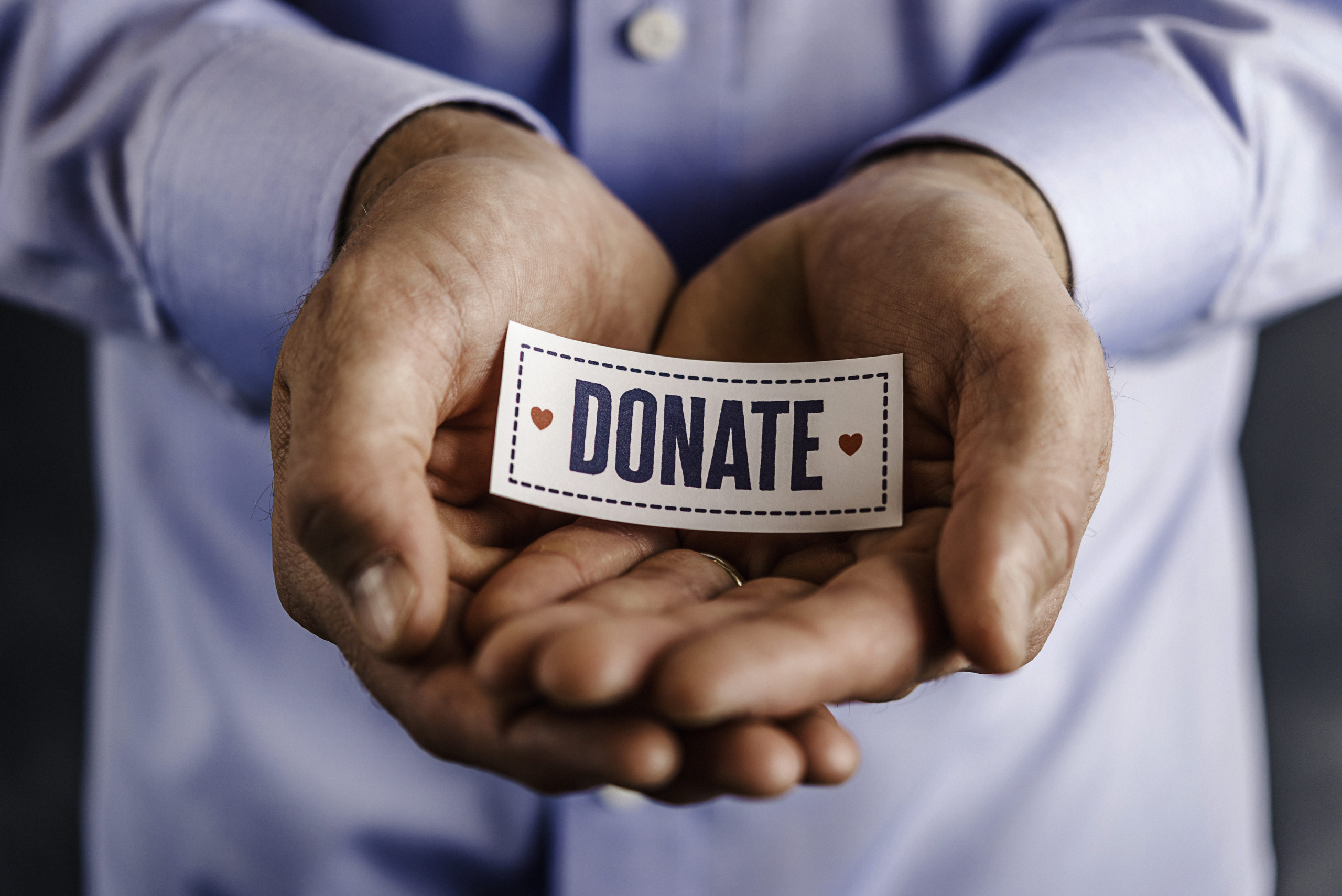 Male hands holding sign reading donate